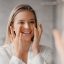 imagine cu o persoană care aplică cremă pe fața ei uscată